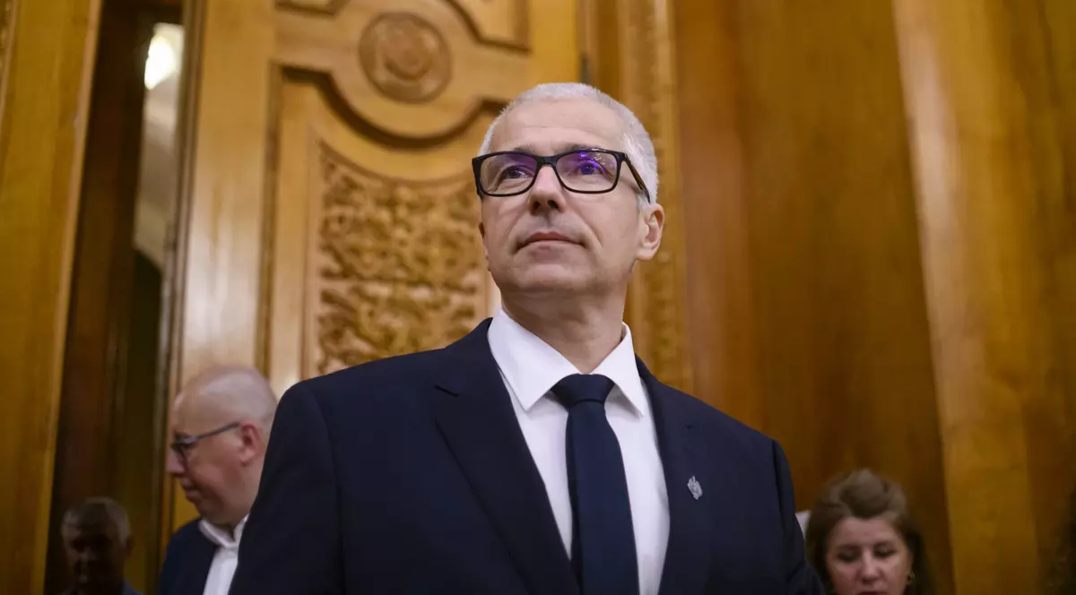 Radu Marinescu surprins în Parlament. Poartă un sacou negru, o cămașă albă și o cravată neagră. Radu Marinescu poartă și ochelari, care au ramele negre.