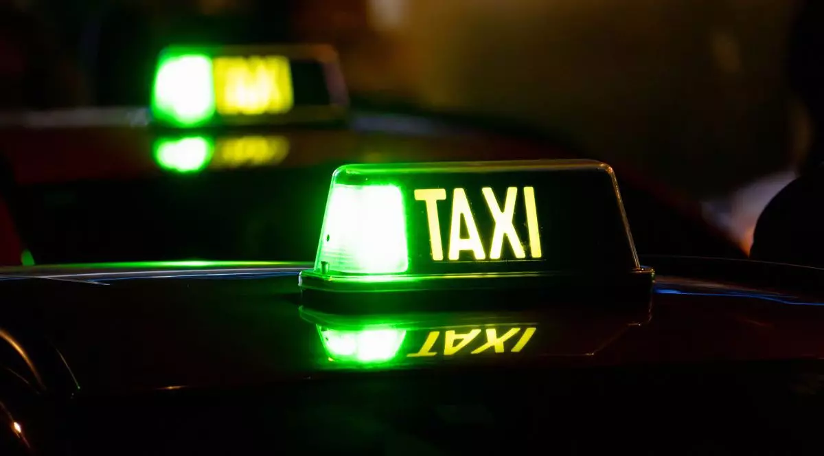 O mașină taxi din care se vede plafonul și care arată că este liberă pentru pasageri, fotografie făcută pe timp de noapte