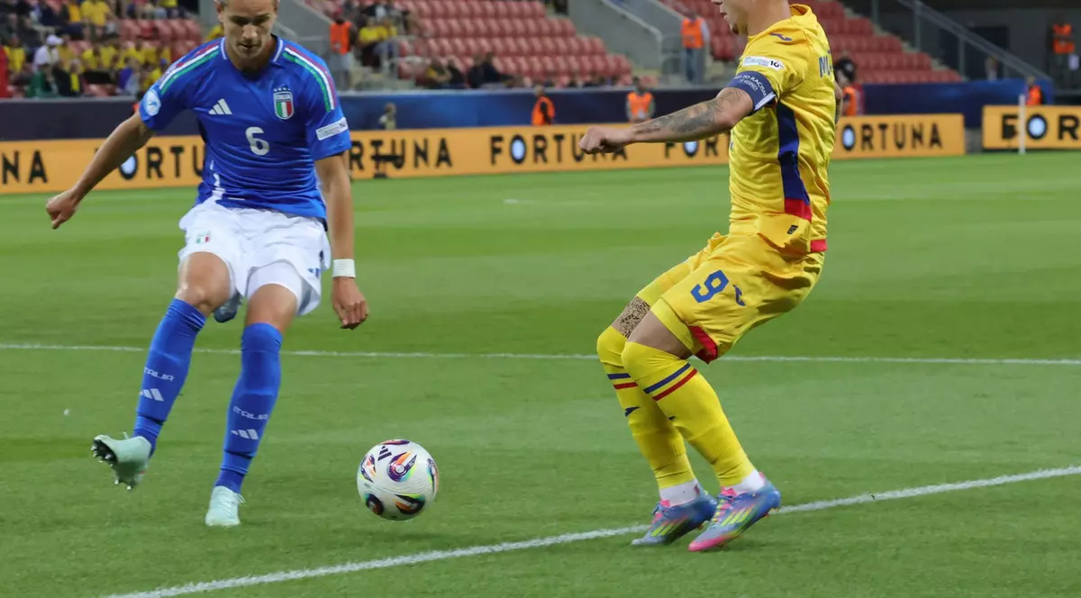 un jucator italian in albastru si un jucator roman in galbenin duel pe teren