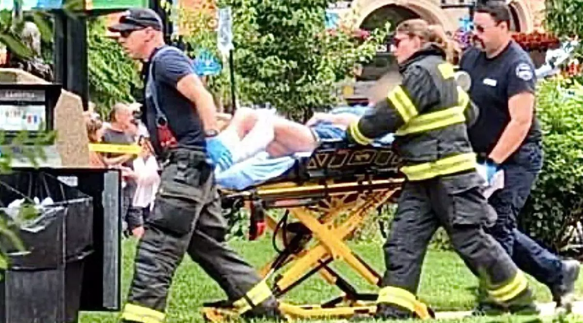 Doi oameni de la ambulanță și încă un bărbat cară pe targă un rănit, pe jos este iarbă și o zonă verde, Colorado, SUA, 2 iunie 2025