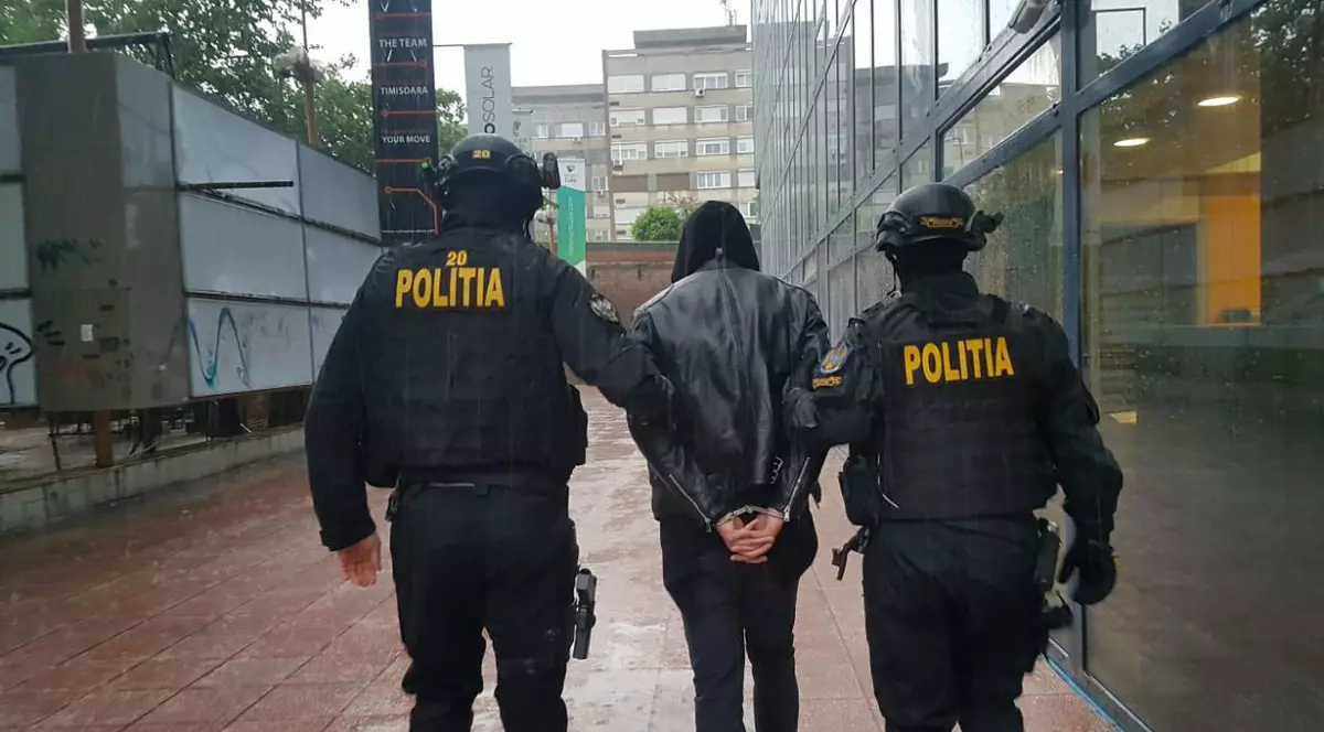 Doi polițiști escortează un bărbat acuzat de tâlhărie