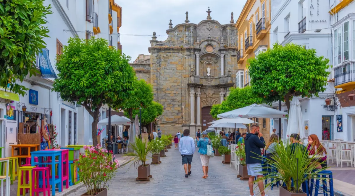 O stradă din Tarifa, Spania, cu terase și oameni care se plimbă.