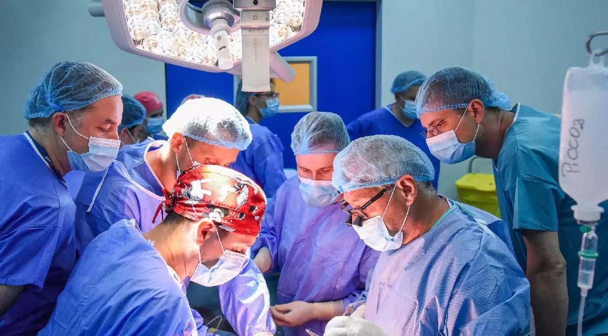 Mai mulți medici, cu halate albastre, in sala de operatie