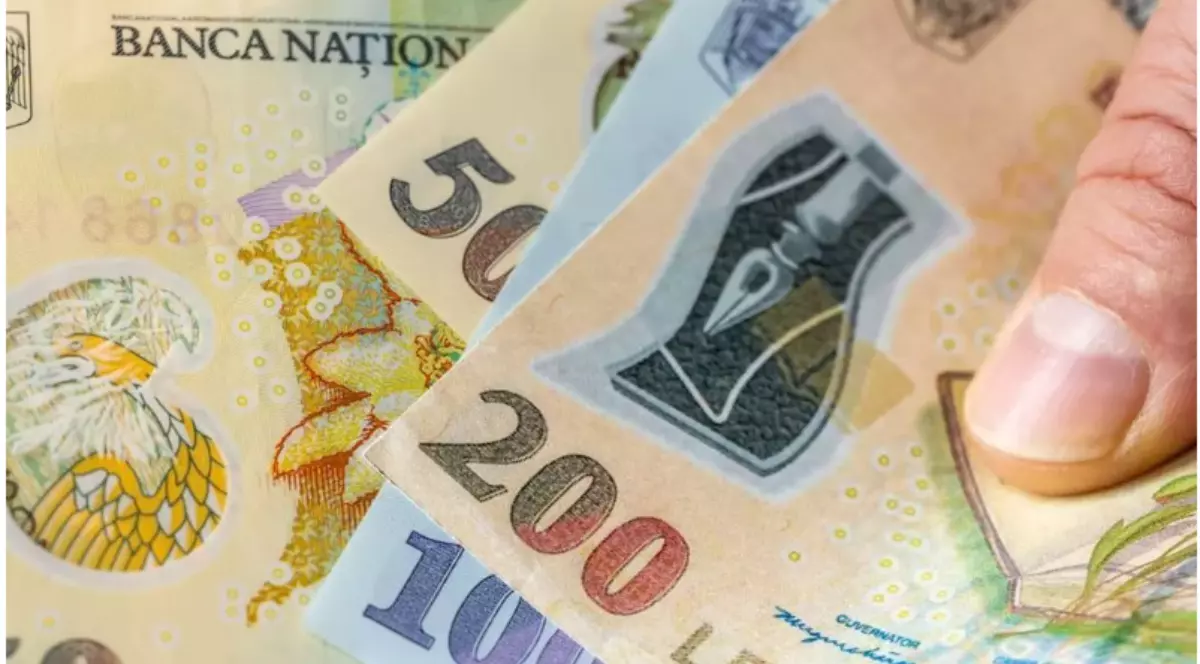 În imagine, un bărbat ține în mână mai multe bancnote