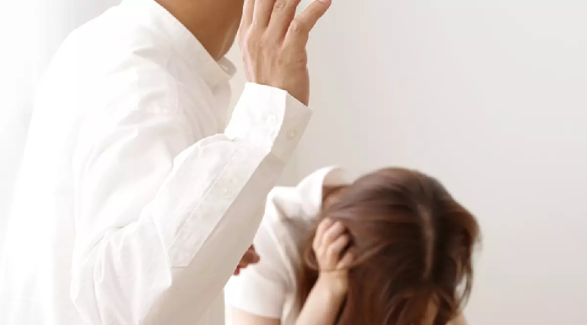 un bărbat ridică mâna să lovească o femeie care stă ghemuită și plânge