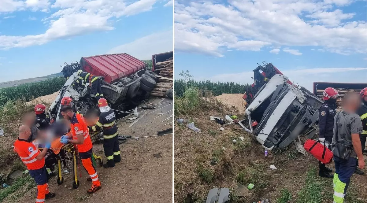 camion roșu cu remorcă, răsturnat pe marginea drumului. cabina camionului este grav avariată și înclinată e o parte, iar remorca este răsturnată, cu lemne care s-au împrăștiat pe marginea drumului. În apropierea cabinei camionului se află mai mulți salvatori și pompieri sunt în jurul unui pacient pe targă. Aceștia poartă echipamente de protecție: uniformă portocalie cu dungi reflectorizante pentru paramedici și uniforme negre cu galben pentru pompieri.