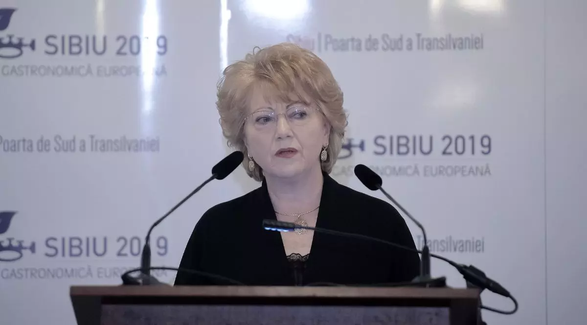 Astrid Fodor, având o privire serioase, îmbrăcată într-o rochie neagră decoltată, în timpul unei conferințe de presă la Clubul Diplomaților din București, noiembrie 2018