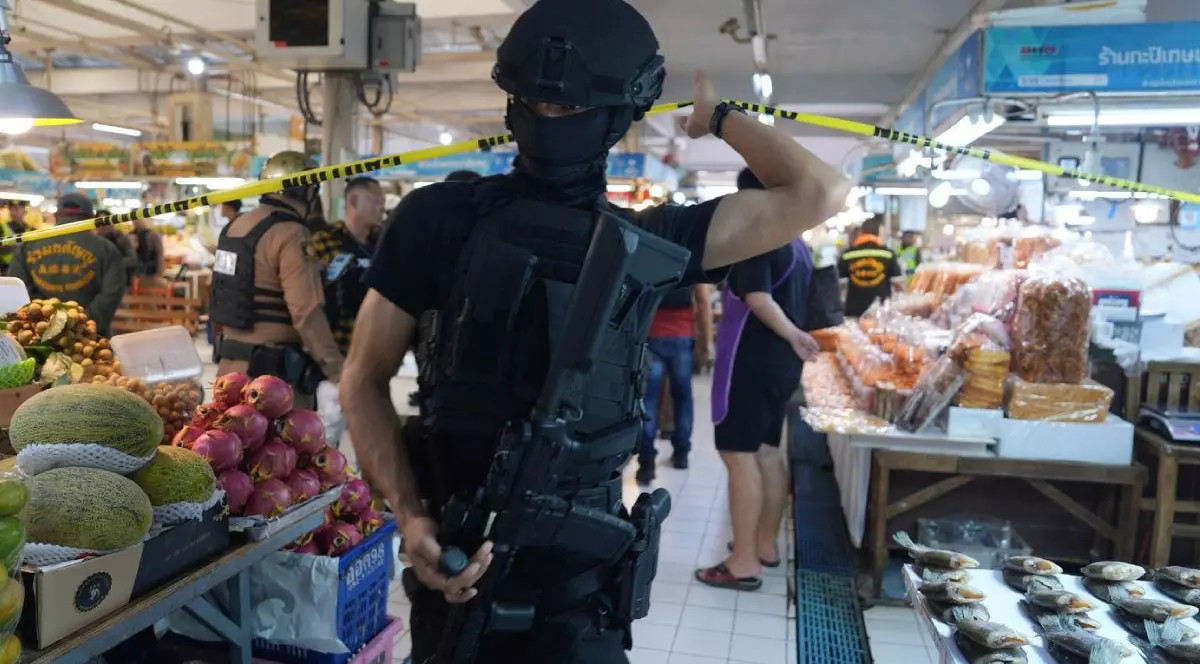 Mascați care trec o bandă de politie după un atac armat intr-o piață din Bangkok, se vad tarabe cu fructe si legume si alti oameni in fundal, 28 iulie 2025