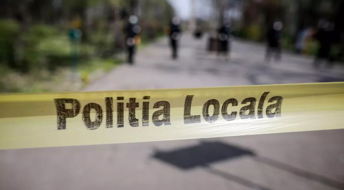 banderolă galbenă cu textul „Poliția locală” prinsă în capătul unei străzi pietruite