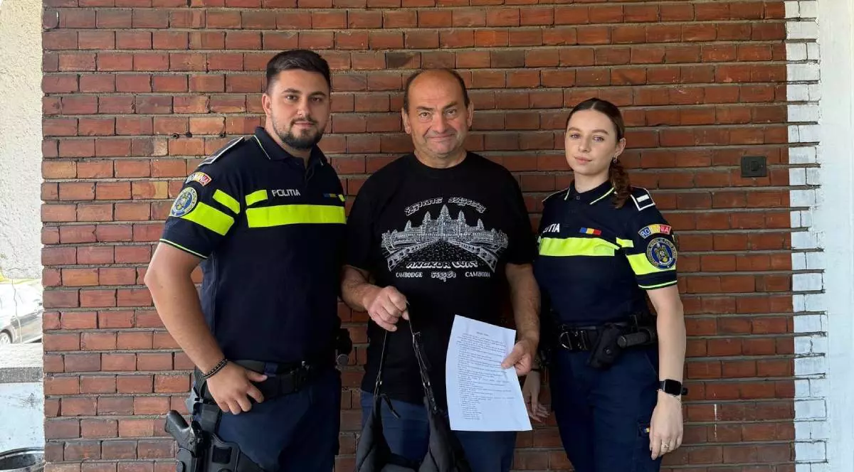 Bărbatul din Alba în timp ce ținea geanta plină cu bani pe care a returnat-o în mână, fotografiat alături de doi polițiști de la IPJ Alba
