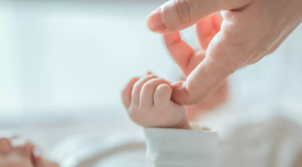 Mână de bebeluș nou-născut ținând degetul unui adult