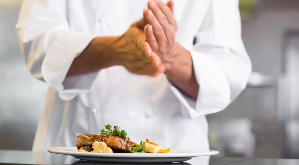 Imagine cu un bucătar și o farfurie plină cu carne, broccoli și conopidă