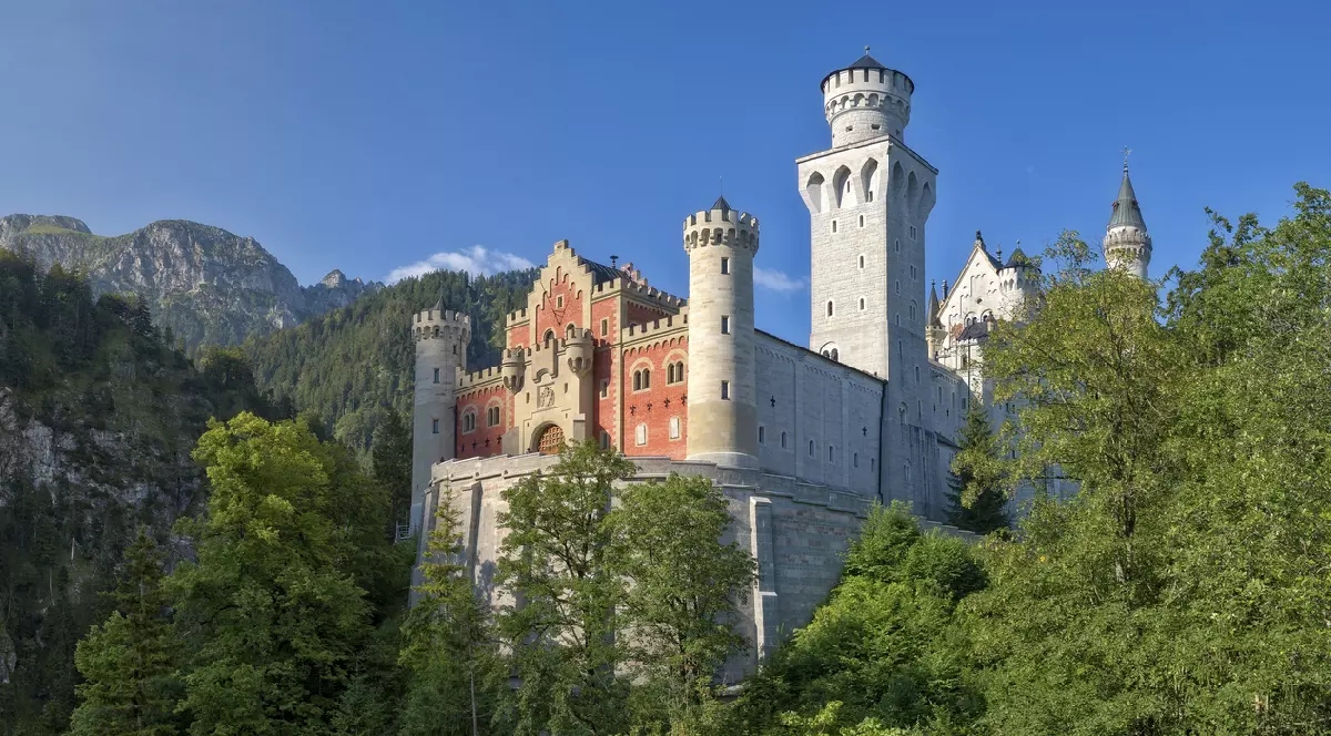 Vedere frontală a fațadei Castelului Neuschwanstein cu zona de intrare și curtea exterioară pe vreme frumoasă, Schwangau, Germania