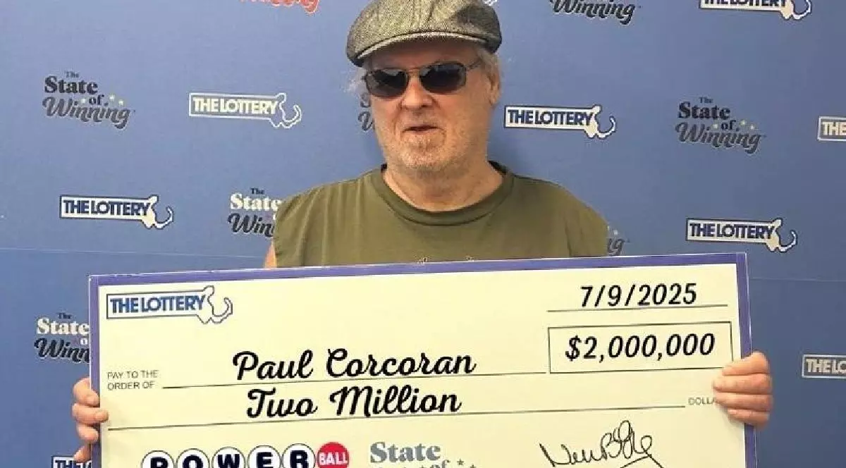 Bărbat care ține în mâini un cec uriaș în valoare de 2 milioane de dolari, câștigat la loteria Powerball din Massachusetts.