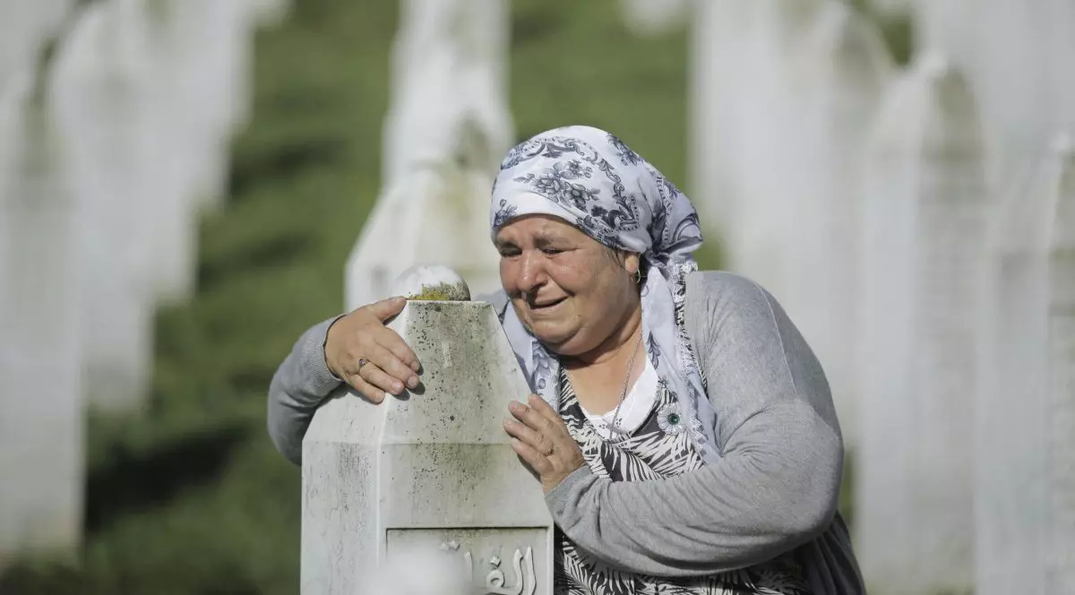 O femeie plânge asupra unui mormânt a unei victime din masacrul de la Srebrenica.