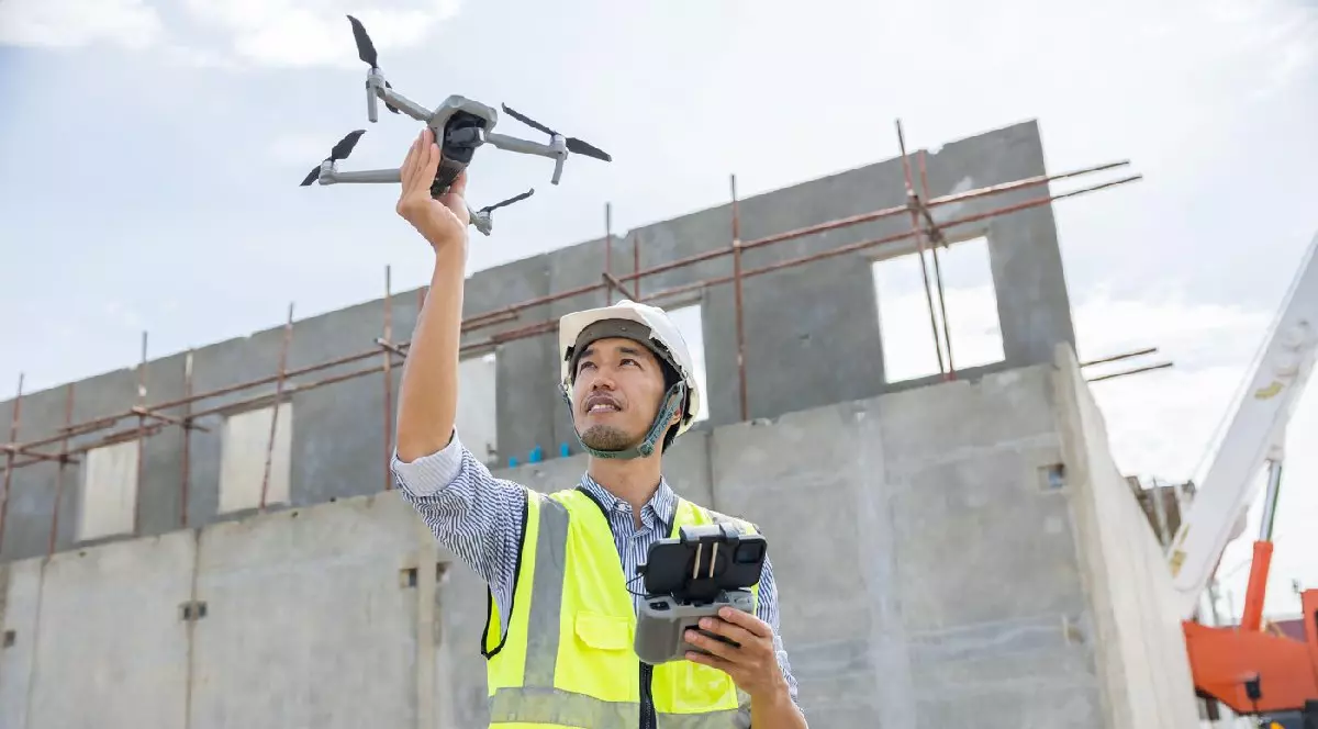 Inginer constructor utilizează o dronă pentru a inspecta șantierul din aer,