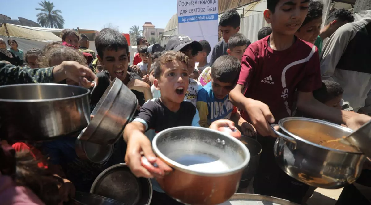 Un copil palestinian întinde oala în care vrea să primească ajutoare umanitare.