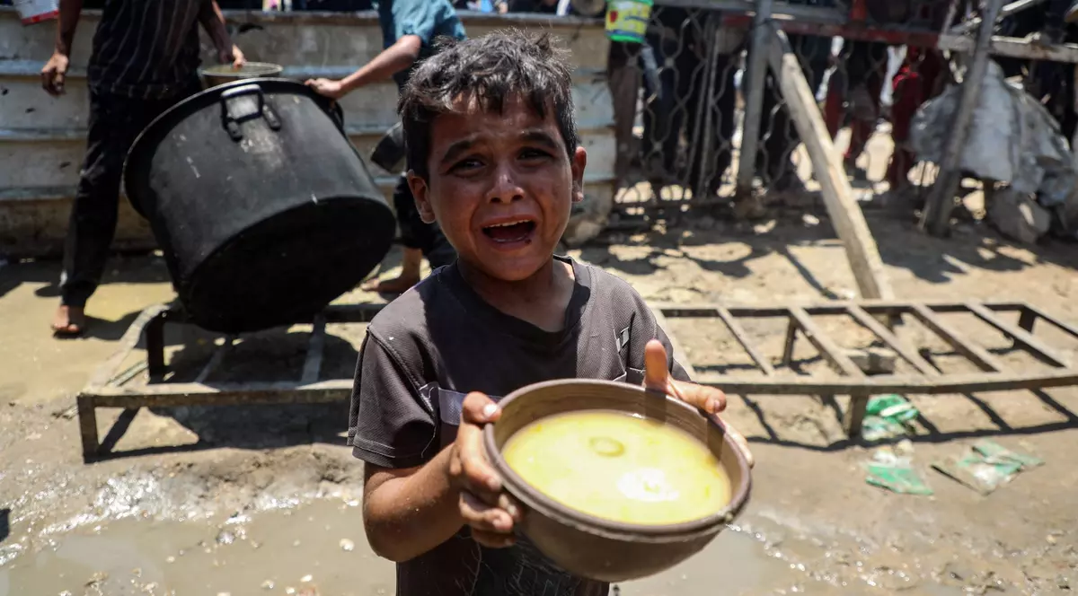 Imagine cu un copil care ține în mâini un bol cu mâncare, în Gaza.