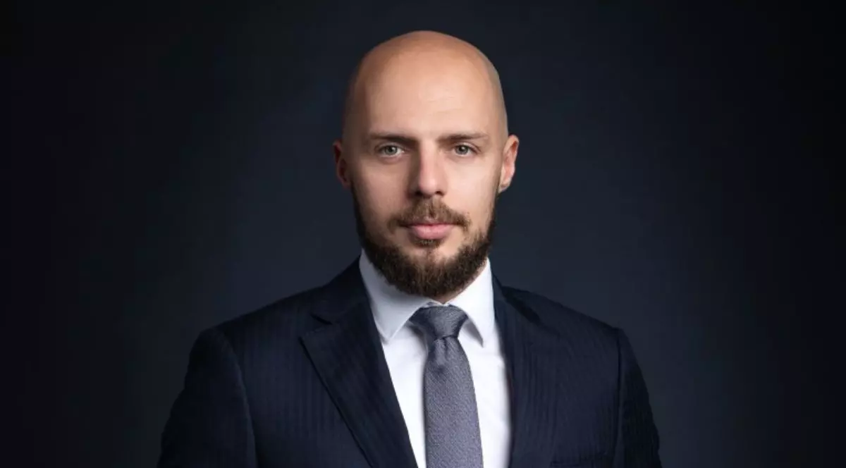 Cristian Pelivan, directorul executiv ARMO, îmbrăcat în costum negru, cu cămașă albă și cravată gri, pe un fundal negru