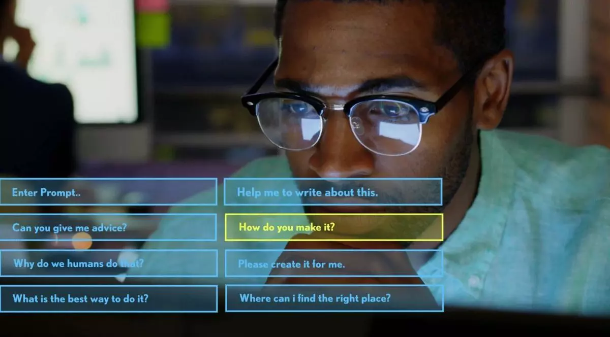 Folosind computerul, un bărbat de culoare, cu ochelari la ochi, interacționează cu o interfață de inteligență artificială pentru asistență