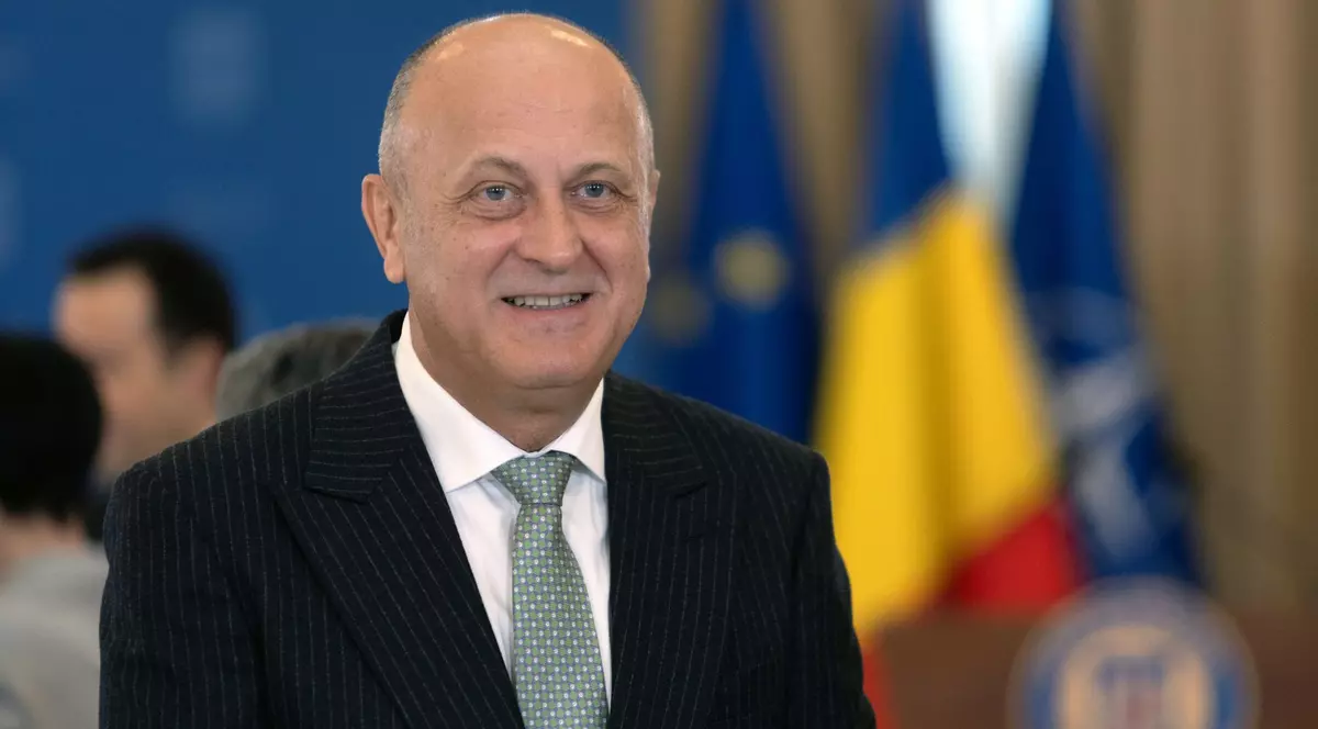 Dan Șucu surprins zâmbind la conferința România OCDE, organizată în aprilie 2025 la Palatul Cotroceni. Poartă un sacou negru, o cămașă albă și o cravată verde cu buline albe
