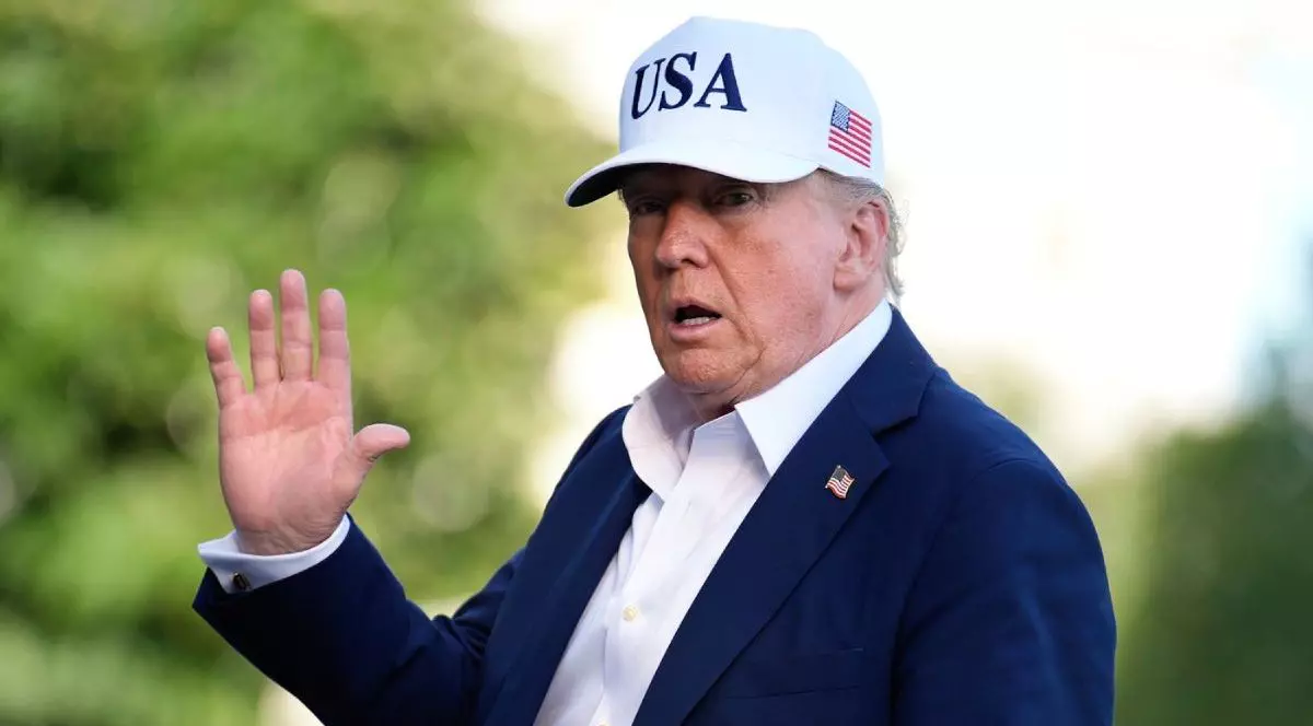 Președintele SUA, Donald Trump, in aer liber, cu o sapca alba pe cap, inscriptionata USA si steagual Americii, un sacoul inchis la culoare si o camasa albă, cu mana dreapta ridicata in semn de salut, 7 iulie 2025, CAsa Albă, Washington, DC