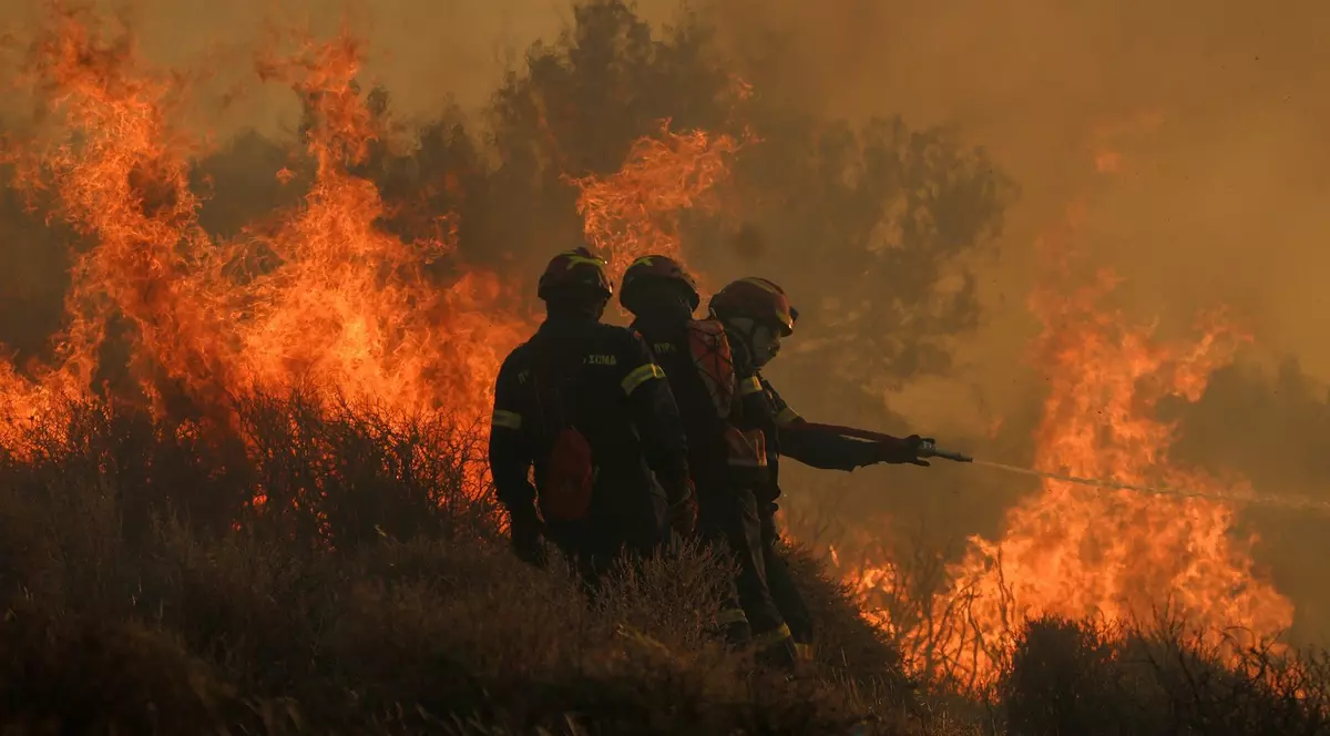 Imagine cu trei pompieri care se luptă cu flăcările din Creta, Grecia. Imaginea a fost surprinsă în iulie 2025