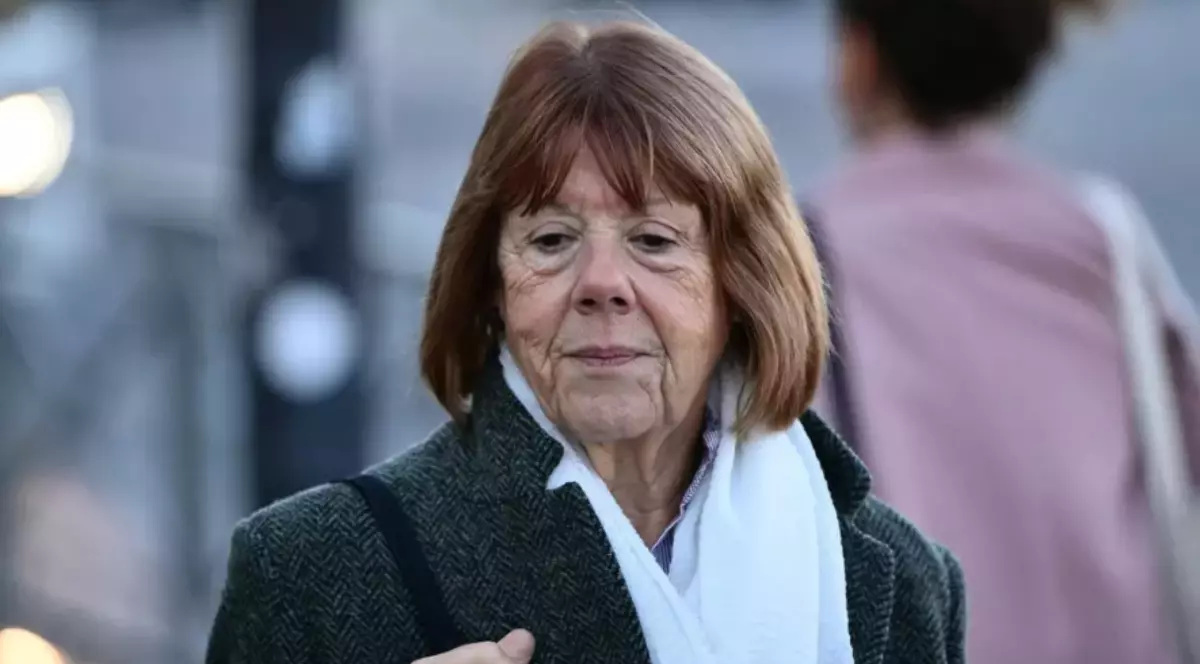 Gisele Pelicot, îmbrăcată în palton gri, cu o geantă pe umăr, privește în jos