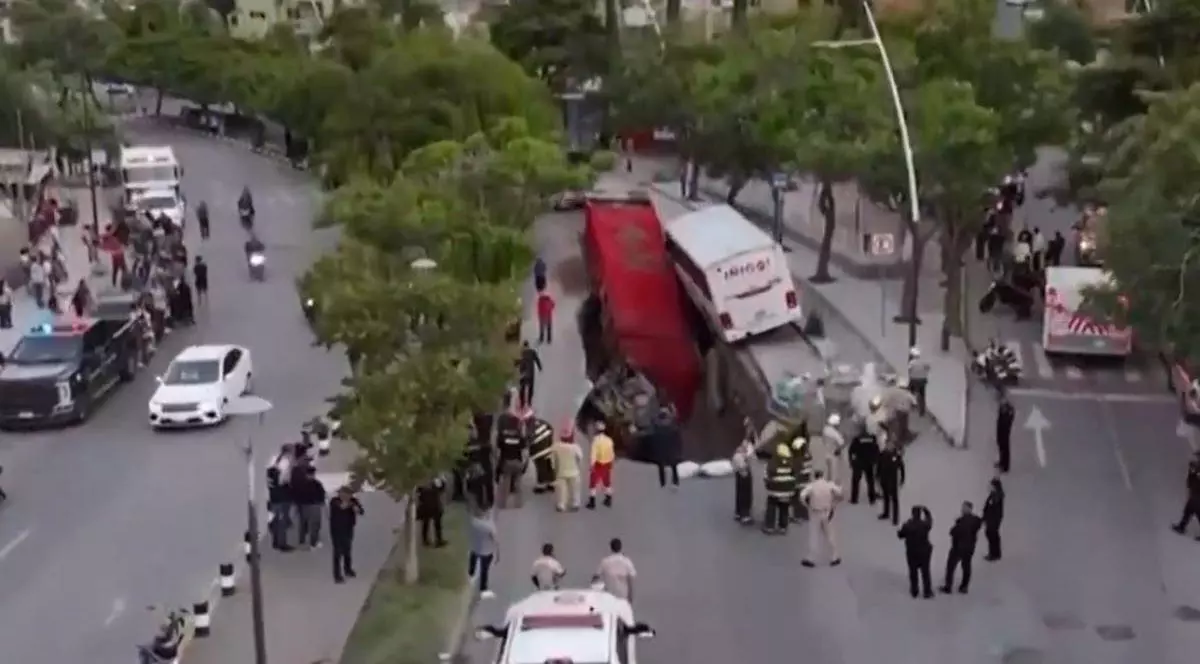 Imagine cu autocarul și camionul în groapa uriașă din Mexic. În jur se află mai mulți oameni