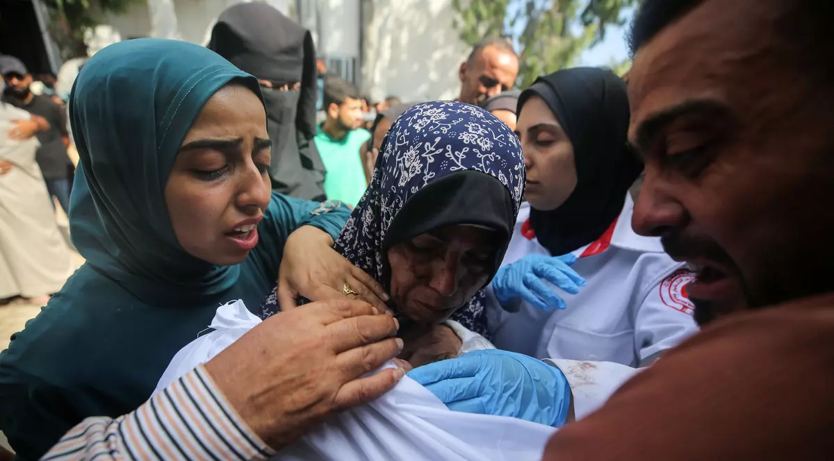 Palestinienii jelesc trupurile învăluite în învăluire ale rudelor, ucise într-un atac israelian, înainte de procesiunea funerară de la spitalul Al-Shifa din orașul Gaza, pe 15 iulie 2025