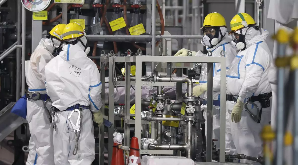 Muncitori îmbrăcați în combinezoane și purând măști verifică sistemul de procesare a apei ALPS, care procesează apa contaminată pentru a o stoca în rezervoarele de la centrala nucleară Fukushima, ianuarie 2020