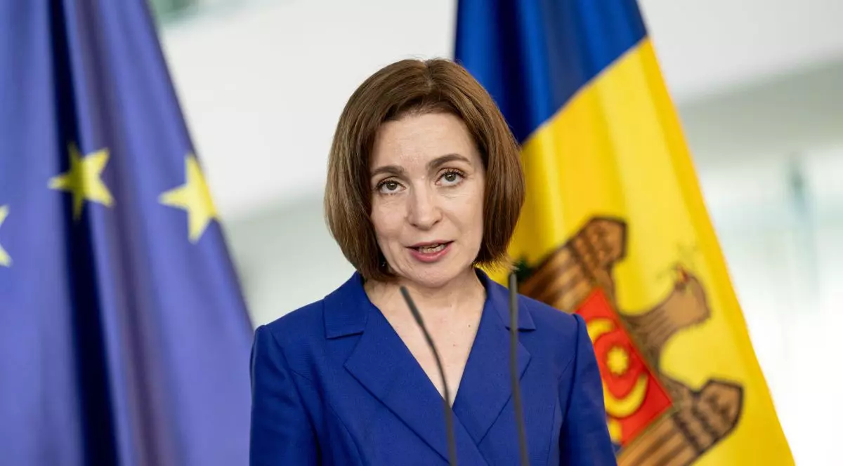 Maia Sandu, îmbăcată într-un taior albastru vorbește în cadrul unei conferințe de presă având în spate steagurile Republicii Moldova și UE, mai 2024
