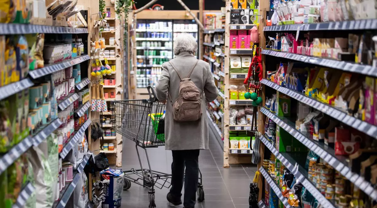O femeie se plimbă printr-un supermarket din Germania cu coșul de cumpărături, martie 2022