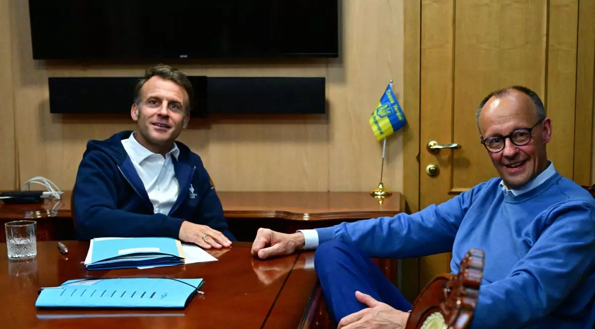 Emmanuel Macron și Friedrich Merz stau la masă în ținute sport la bordul unui tren care merge spre Kiev, mai 2025