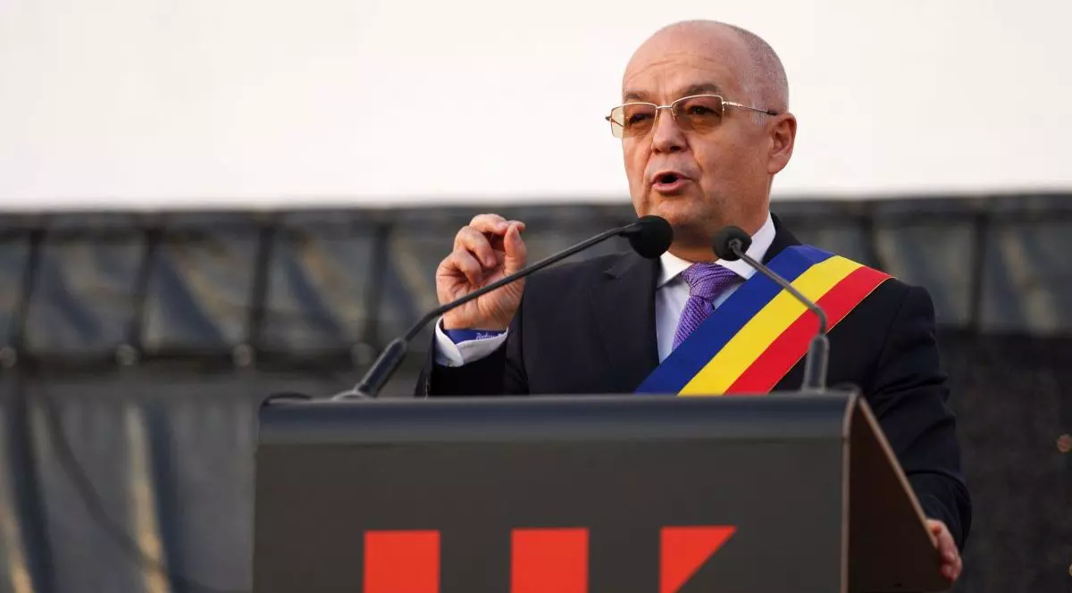 Emil Boc vorbește de la tribună la un eveniment din Cluj, în costum și având o eșarfă tricoloră, iunie 2025