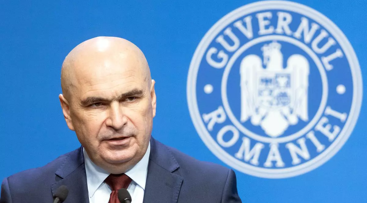Ilie Bolojan vorbește în timp ce pe fundal se vede sigla Guvernului României, iunie 2025