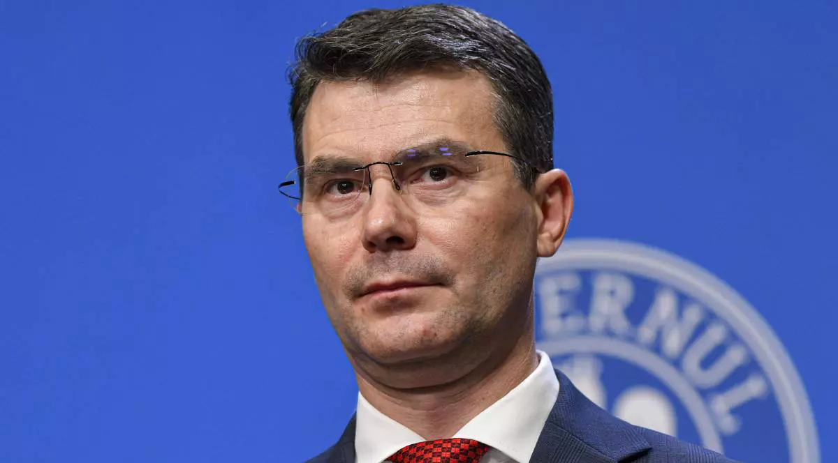Horațiu Moldovan, șeful CNAS, în timpul unei conferințe de presă, poartă un costum albastru și o cravată roșie.