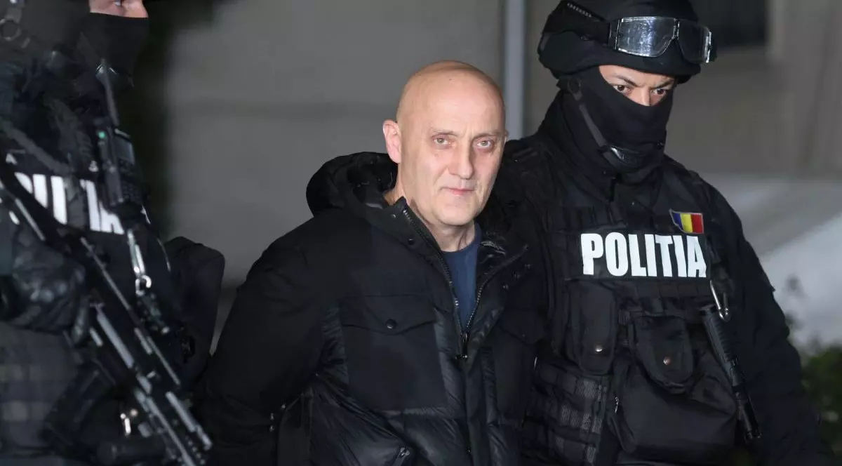 Imagini de noapte cu Horațiu Potra, imbracat in haine negre, este escortat de polițiști mascați în afara sediului IPJ Prahova, în Ploiești, 8 decembrie 2024.