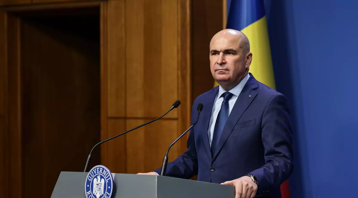 Ilie Bolojan îmbrăcat într-un costum bleumarin, o cămașă albă și o cravată bleumarin, în timpul conferinței de presă de la Palatul Victoria