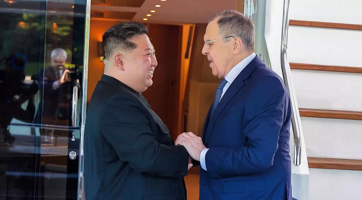 Kim Jong Un, stânga, in costum negru, și ministrul rus de externe, Serghei Lavrov, în sostum albastru, își dau mâna la Wonsan, Coreea de Nord, sâmbătă, 12 iulie 2025.