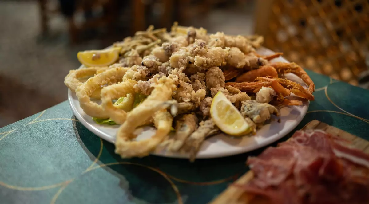 Imagine cu o farfurie plină cu calamar pane, midii pane și lămâie