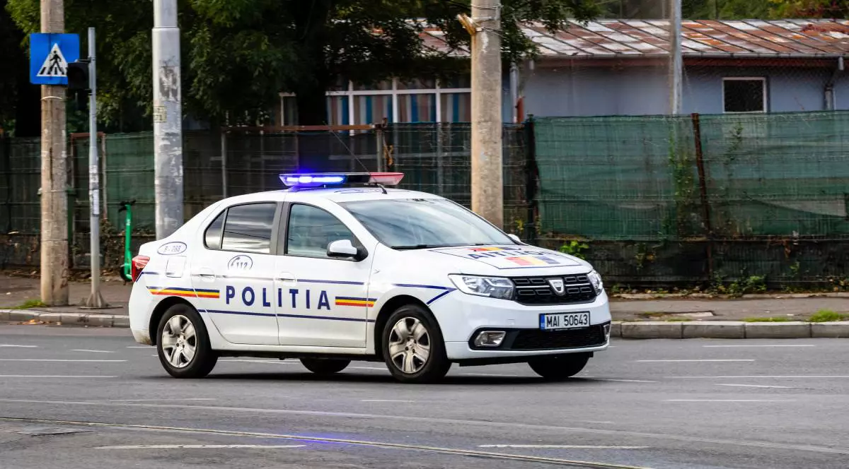 O mașină de poliție mergând pe stradă ziua în oraș cu girofarul pornit
