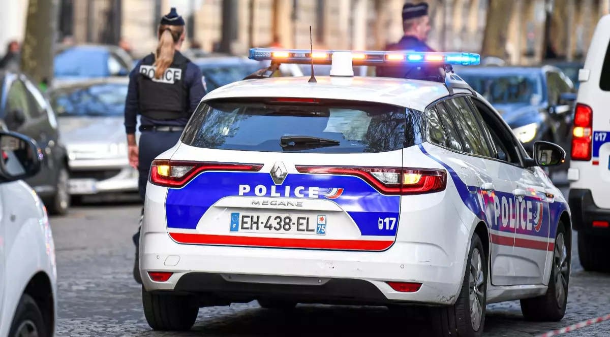 O polițistă lângă o mașină de poliție parcată pe șosea în Franța