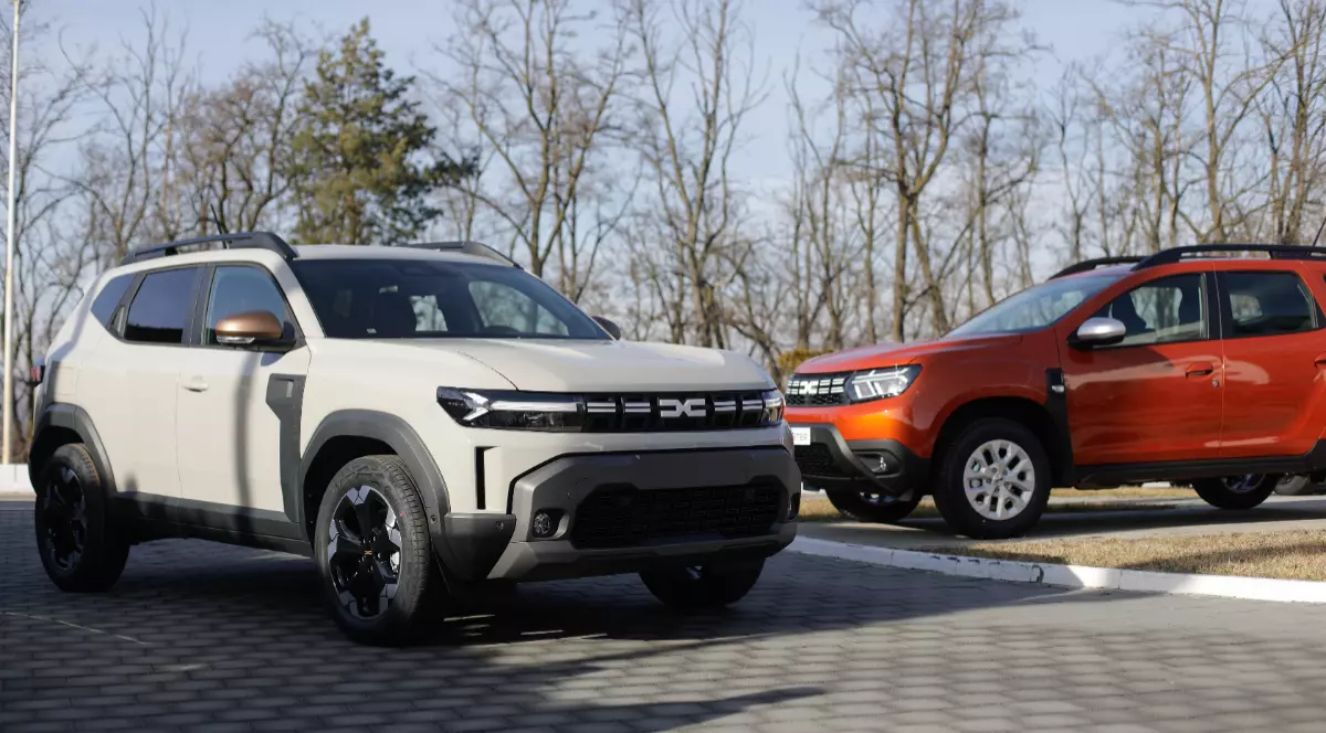 Două mașini marca Dacia. Cea din stânga este albă, iar cea din dreapta este cărămizie