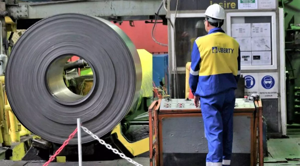 Imagine cu un muncitor Liberty Galați. Poartă o bluză albastră cu galben pe care scrie „Liberty” și o cască albă de protecție. Pantalonii sunt de culoare albastră