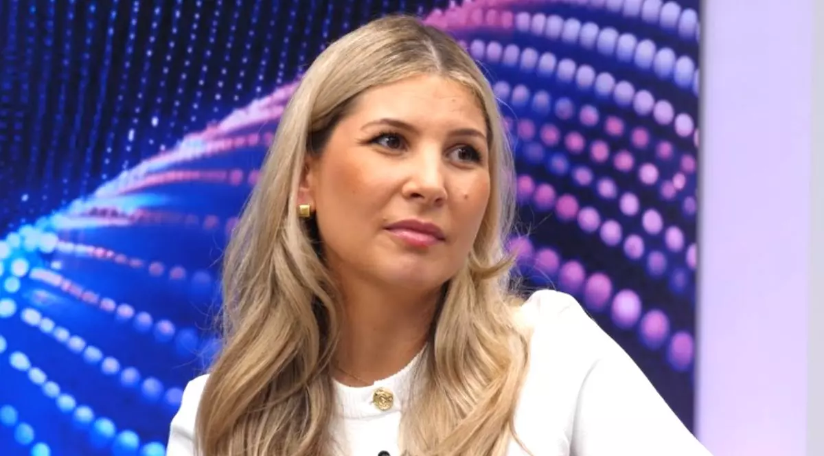 Oana Vlădilă, îmbrăcată cu o bluză albă, în platoul emisiunii Puterea unui Lider de la Libertatea, cu fundal albastru