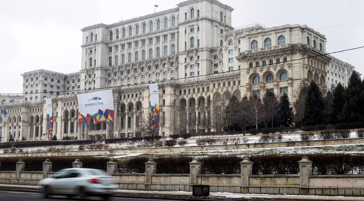 Palatul Parlamentului, văzut de jos, de pe stradă. Prin fața clădirii Parlamentului se poate observa o mașină albă, în mișcare