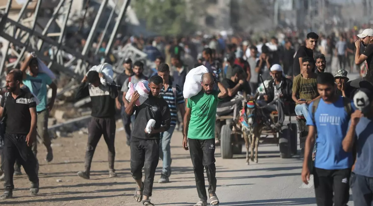 Palestinienii se întorc pe coridorul Netzarim cărând colete cu ajutoare primite de la un punct de distribuție al GHF Foto: Profimedia