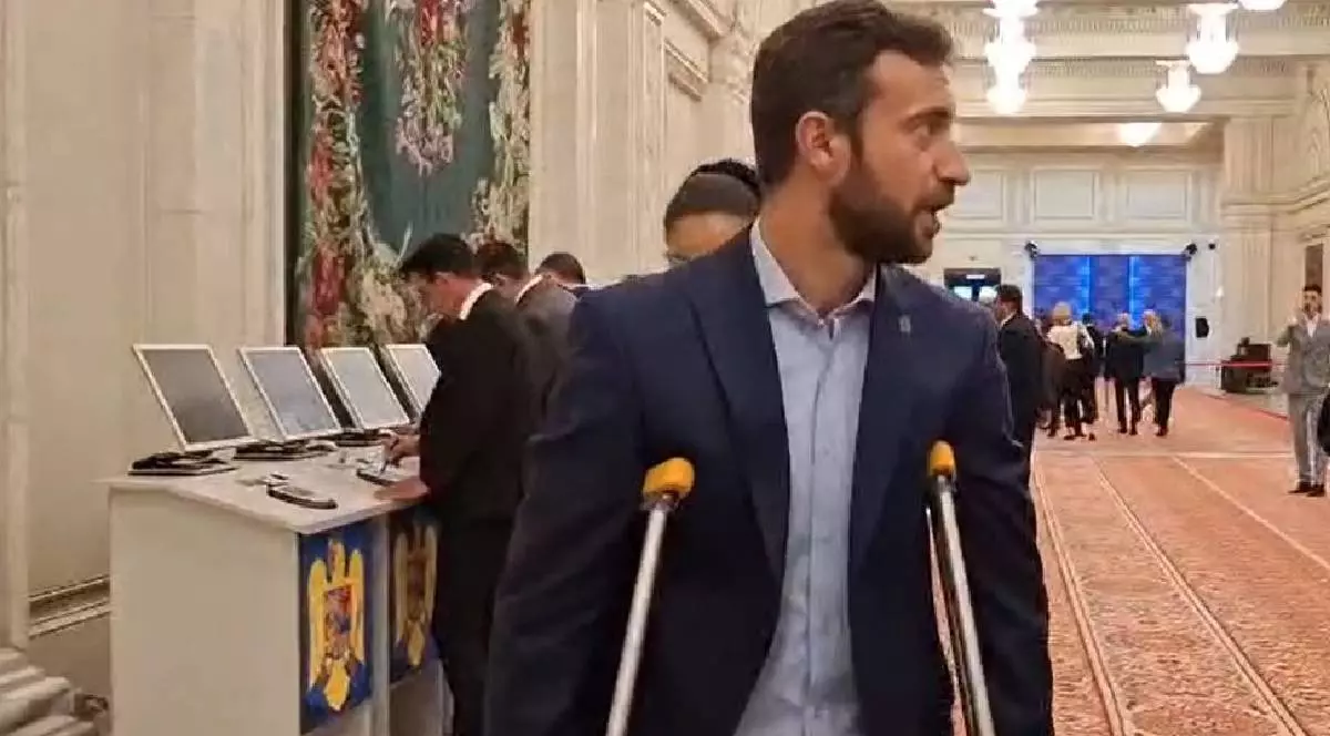Parlamentarul AUR sosit în cârje în Parlament, îmbrăcat la costum.