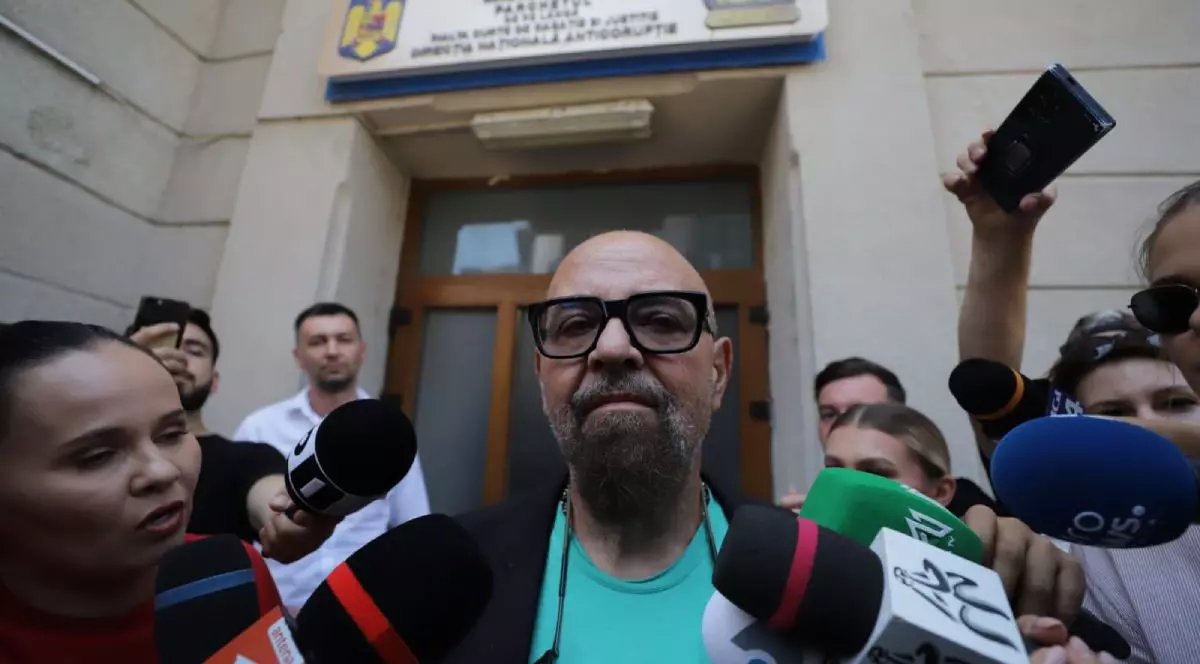 În imagine Piedone, proaspăt ieșit de la DNA, zâmbește camerelor înconjurat de jurnaliști, 23 iulie 2025